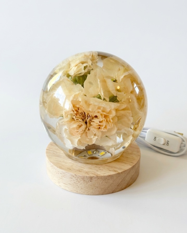 Esfera de resina com flores sobre base de madeira